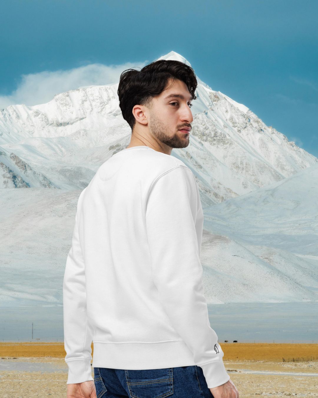DESTINED Premium Sweatshirt Snowfield – Rückenansicht mit Pinguin-Stickerei am Ärmel vor verschneiter Berglandschaft